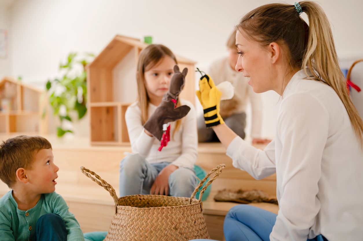 Teacher and preschool children playing with finger puppets