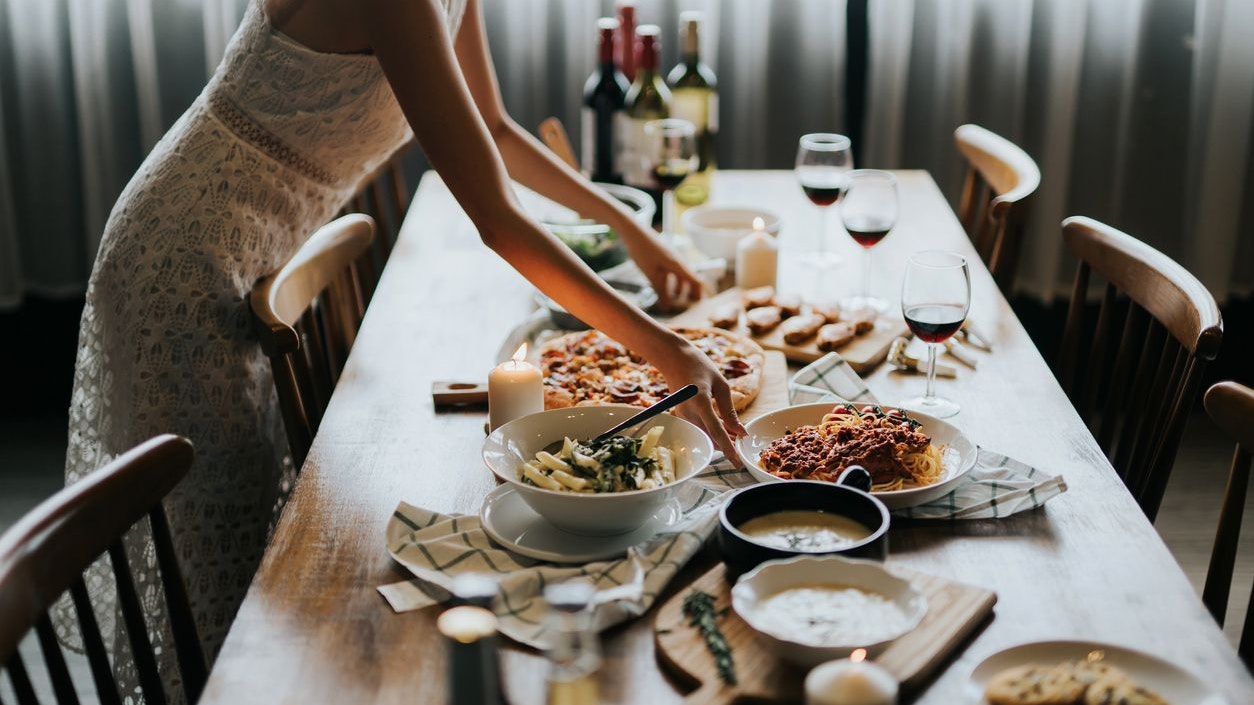 Young Asian woman setting the table and serving food and wine ready for party with friends at home