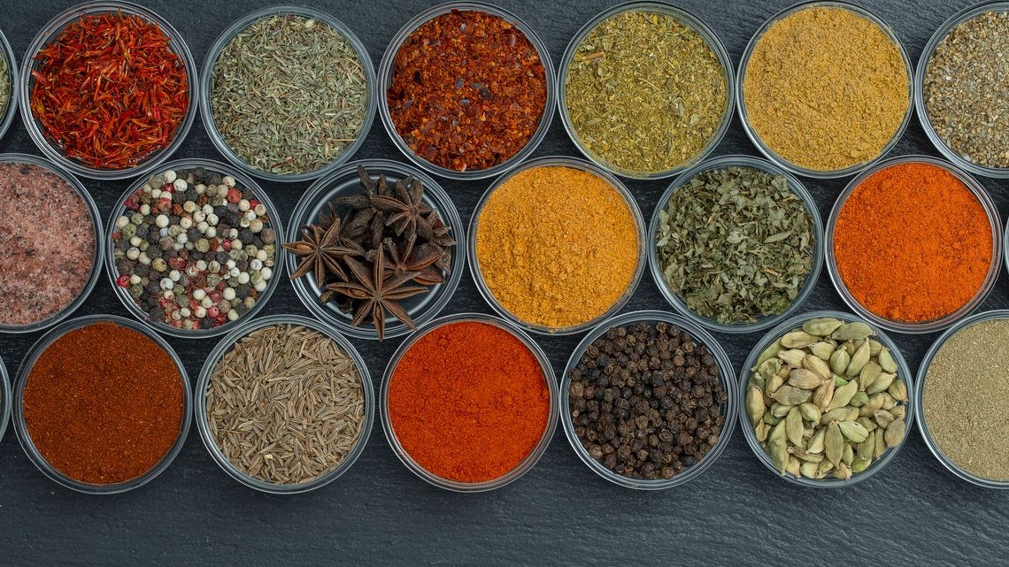 Assortment of aromatic spices, seeds and dry herbs for cooking food on background in small glass bowls, close up, top view, copy space