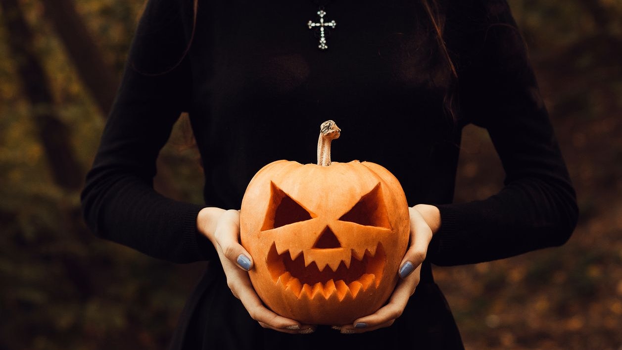 The skinny girl in the guise of a witch holds a lantern jack