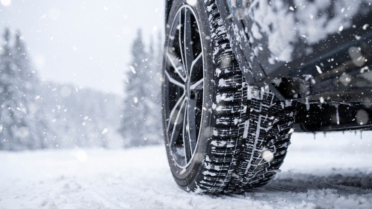 Close-up low angle shot of car tyre on a snowy road in winter.