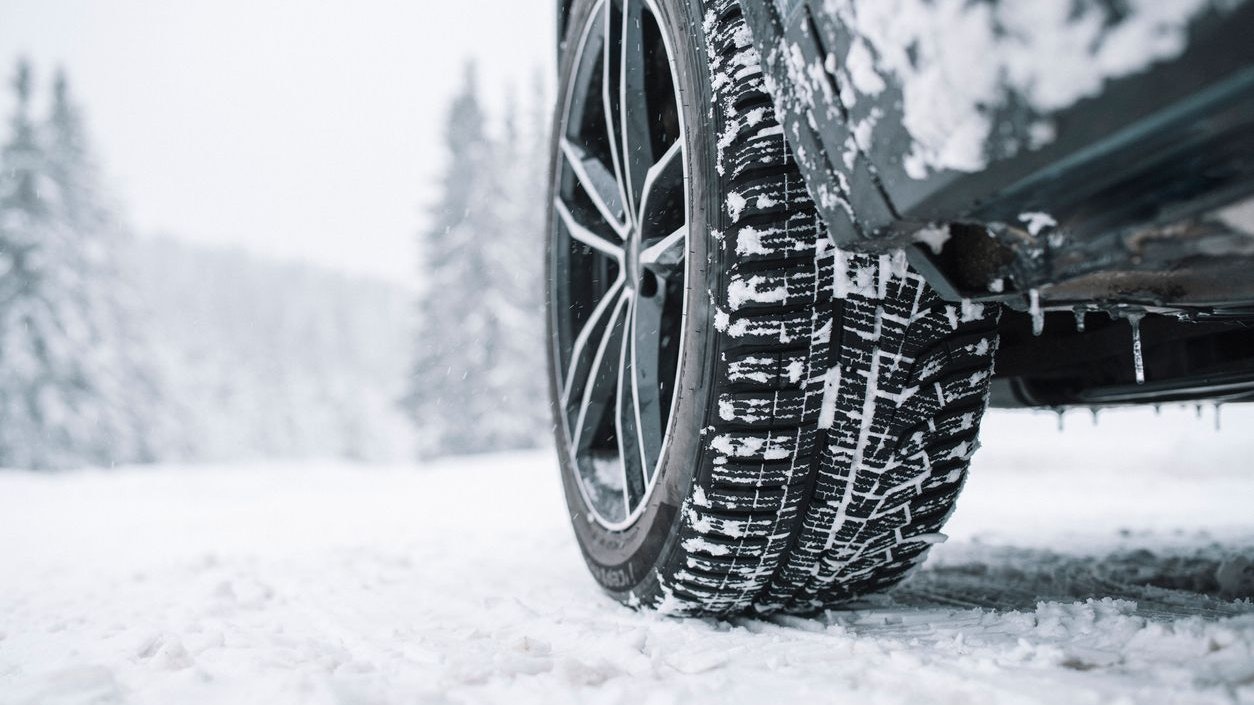 Close up of black car tyre covered with snow on a snowy road