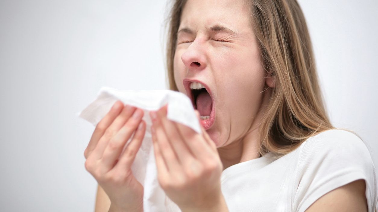 portrait of a young woman with tissue sneezing 