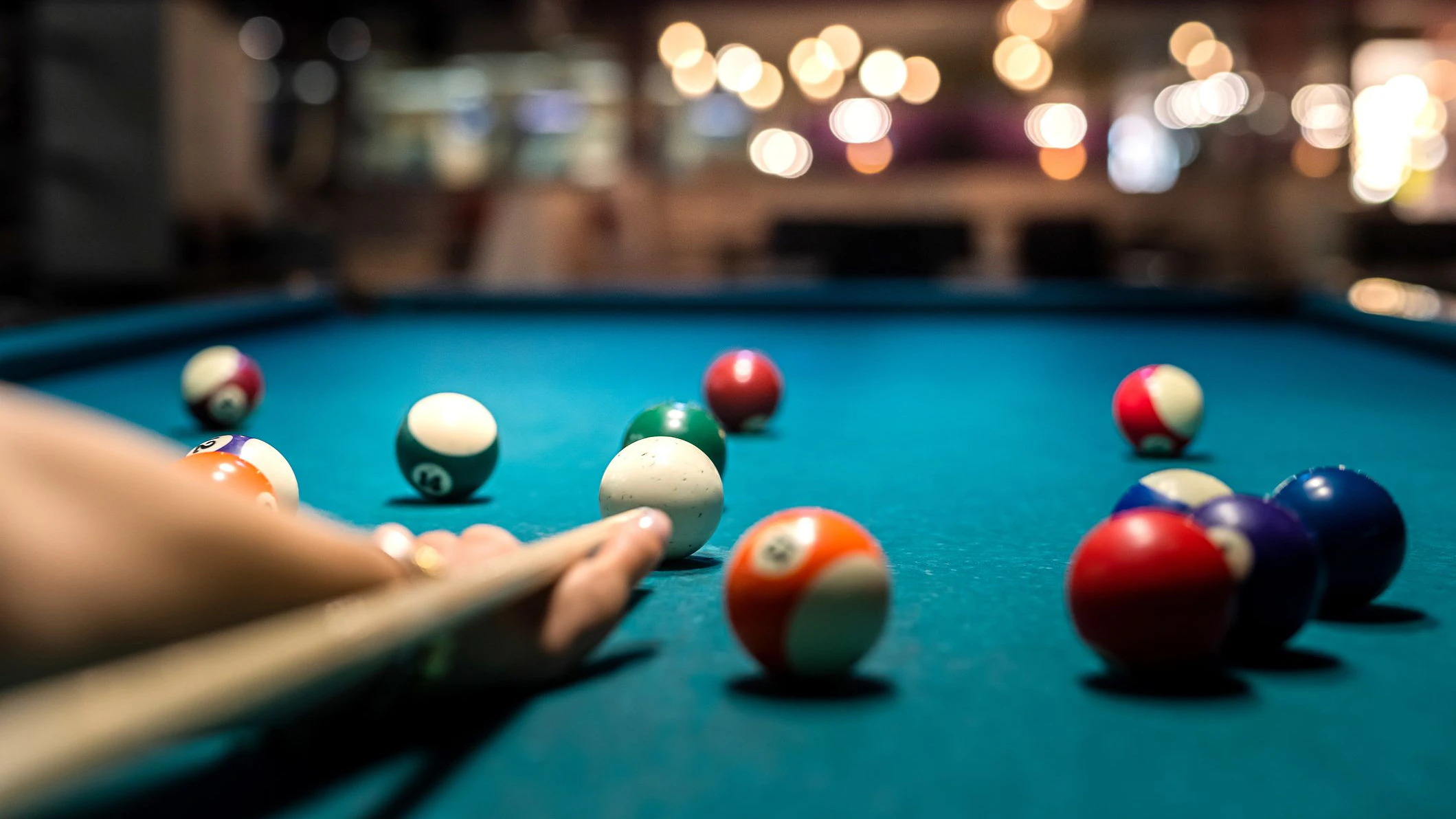 close up of female hand hold cue and preparing aiming to shoot to pool balls. game concept