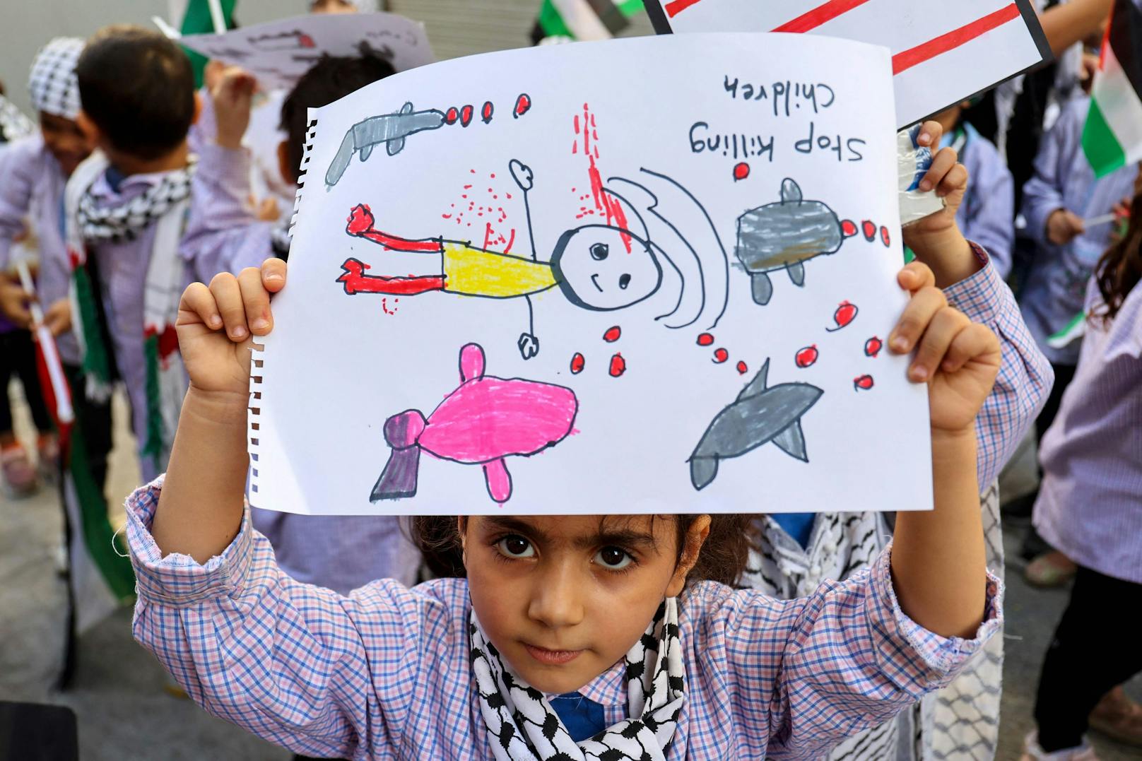 Ein palästinensischer Junge mit einer Zeichnung auf einer Demonstration in Beirut. "Stoppt den Mord an Kindern" steht auf dem Bild geschrieben.