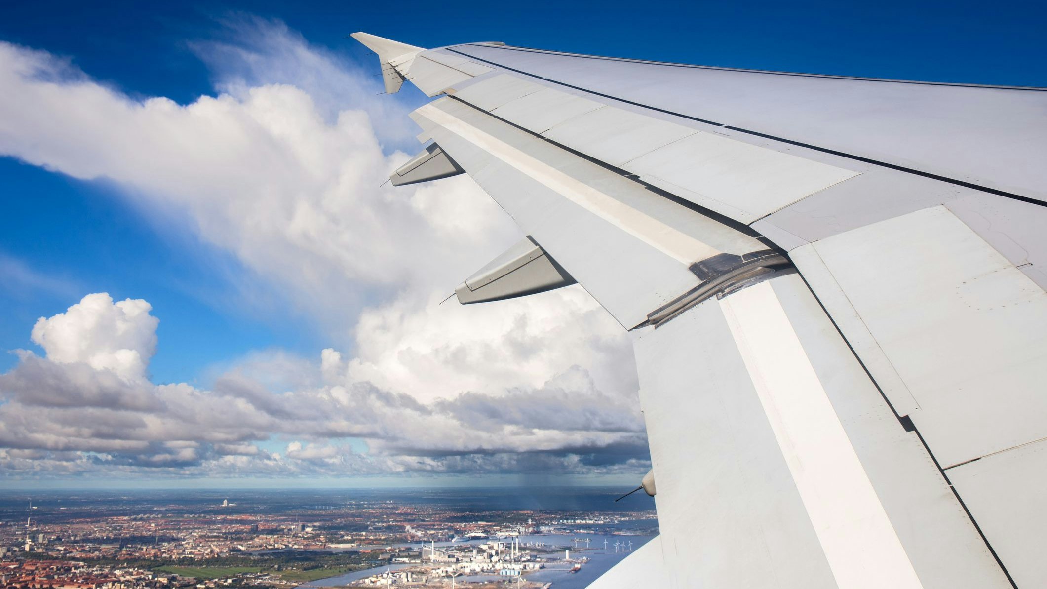 Aerial view of Copenhagen city with petrochemical and power plant industry from window airplane view with clear blue sky and rainy cloud over Copenhagen city, Denmark, during airplane takeoff from Copenhagen Airport