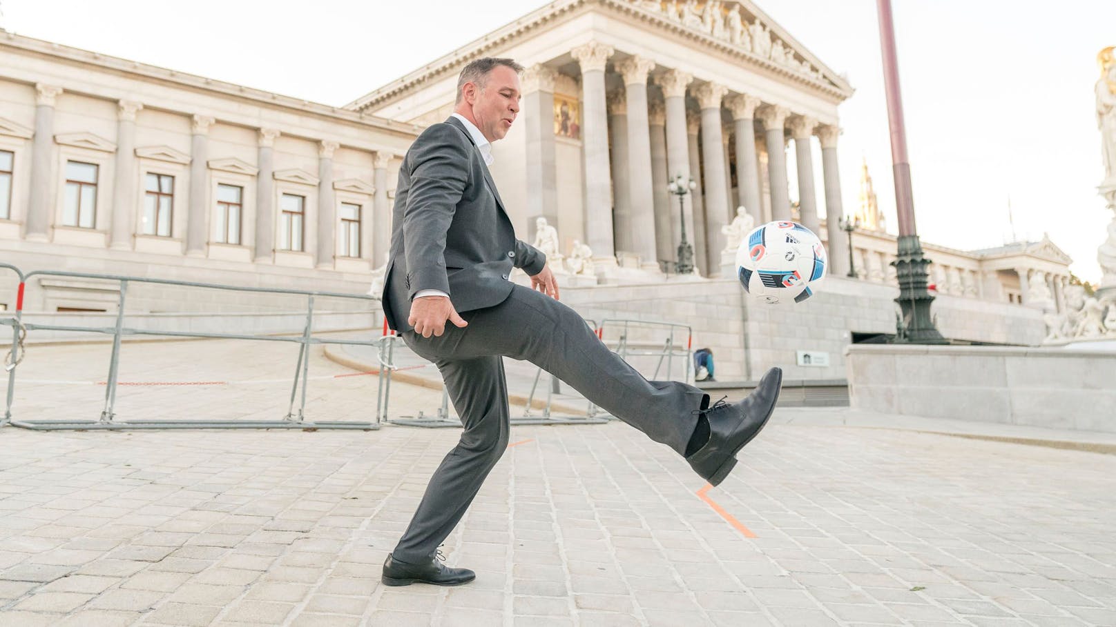 SPÖ-Chef Andreas Babler gaberlt mit einem Fußball vor dem Parlament.