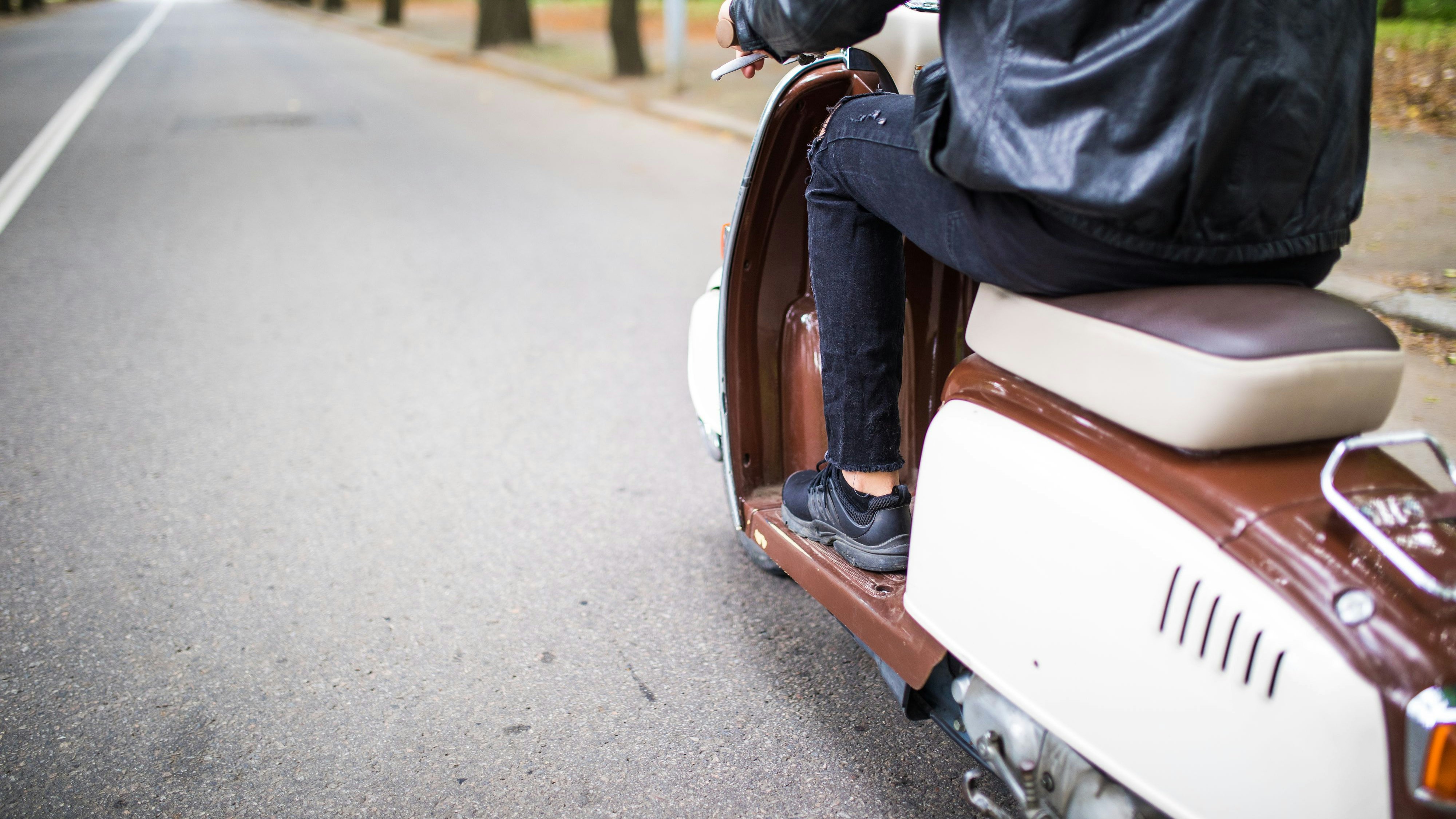 Close up portrait of young man driving scooter on street.