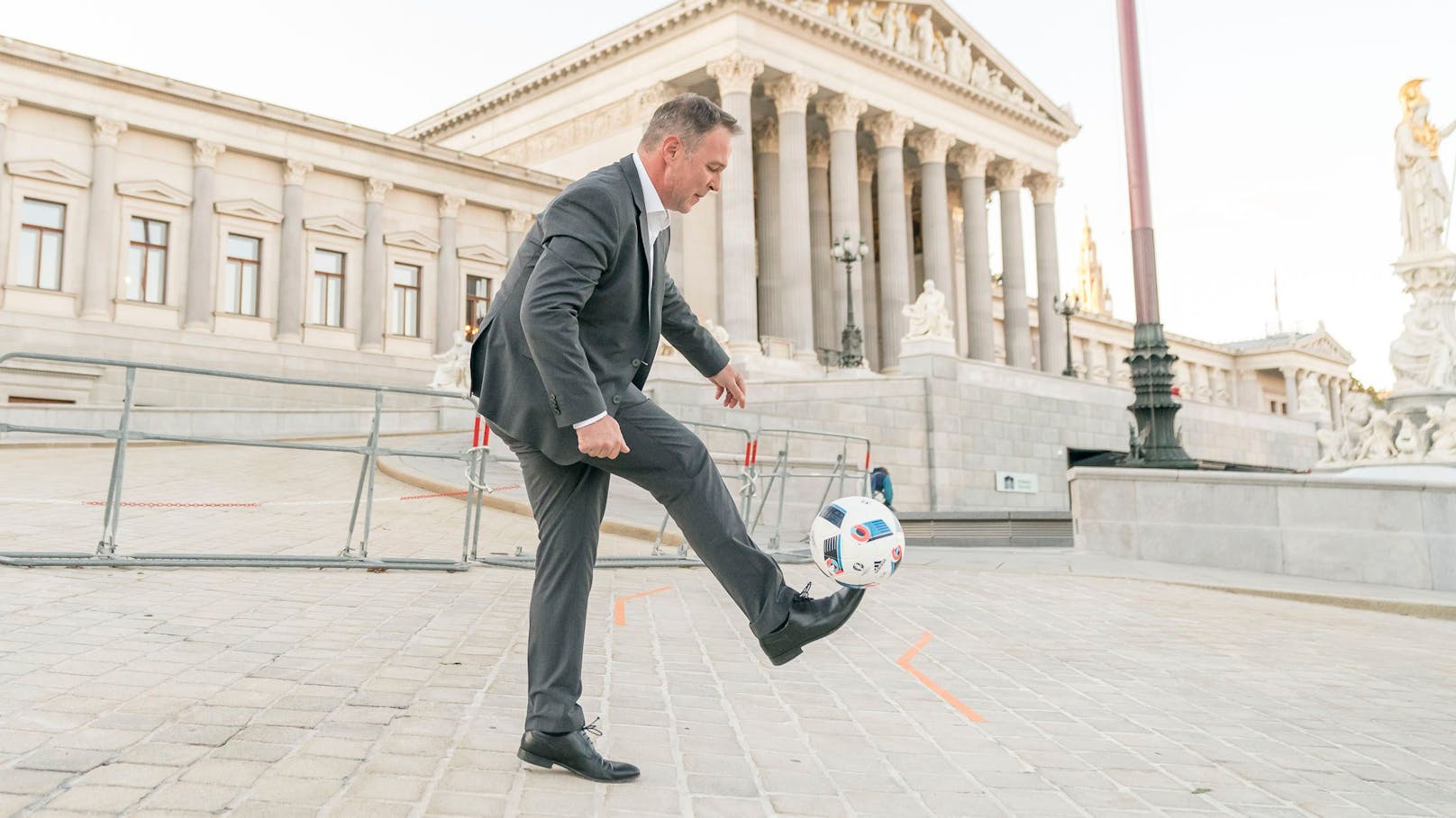 SPÖ-Chef Andreas Babler gaberlt mit einem Fußball vor dem Parlament.