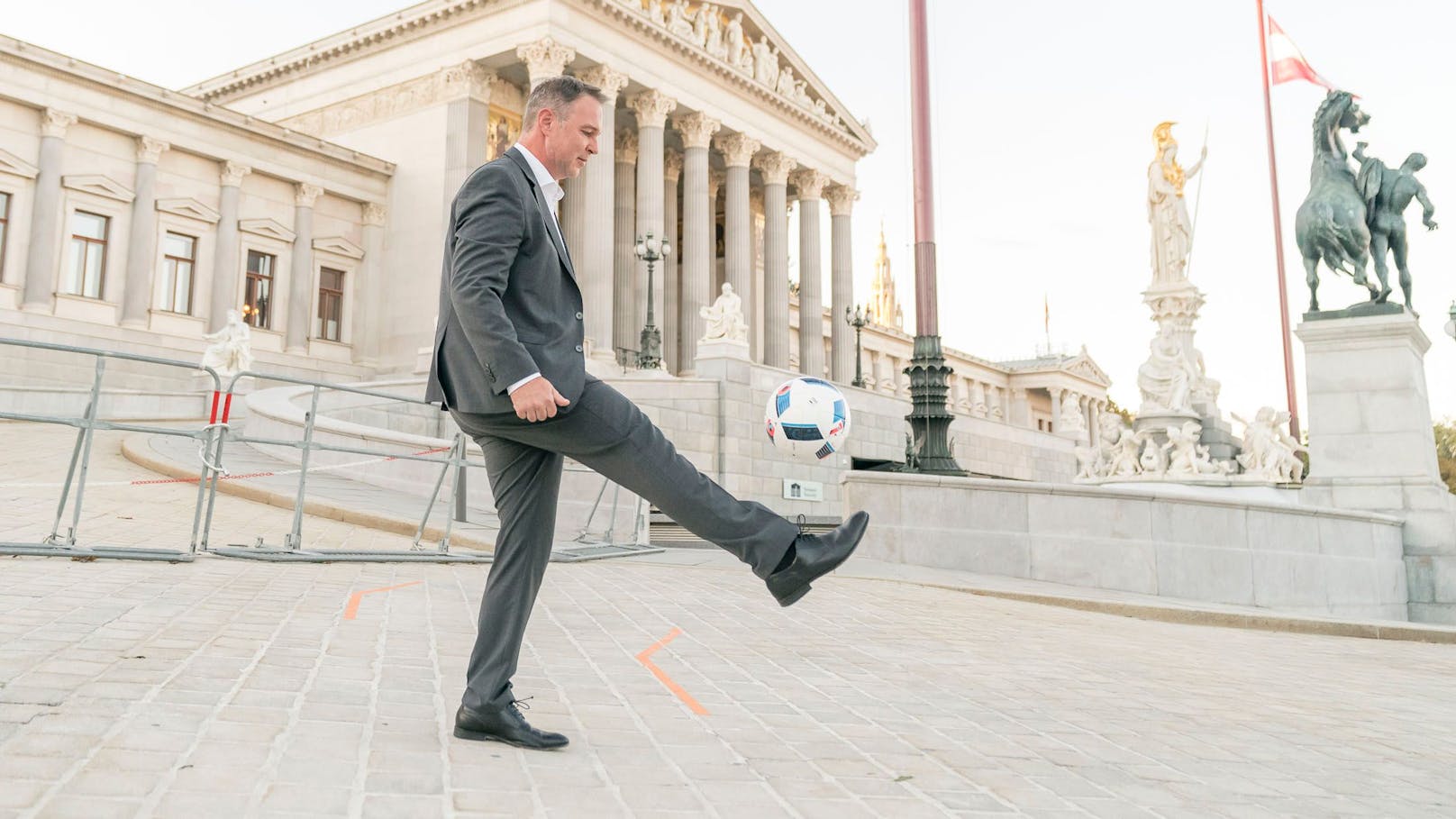 SPÖ-Chef Andreas Babler gaberlt mit einem Fußball vor dem Parlament.