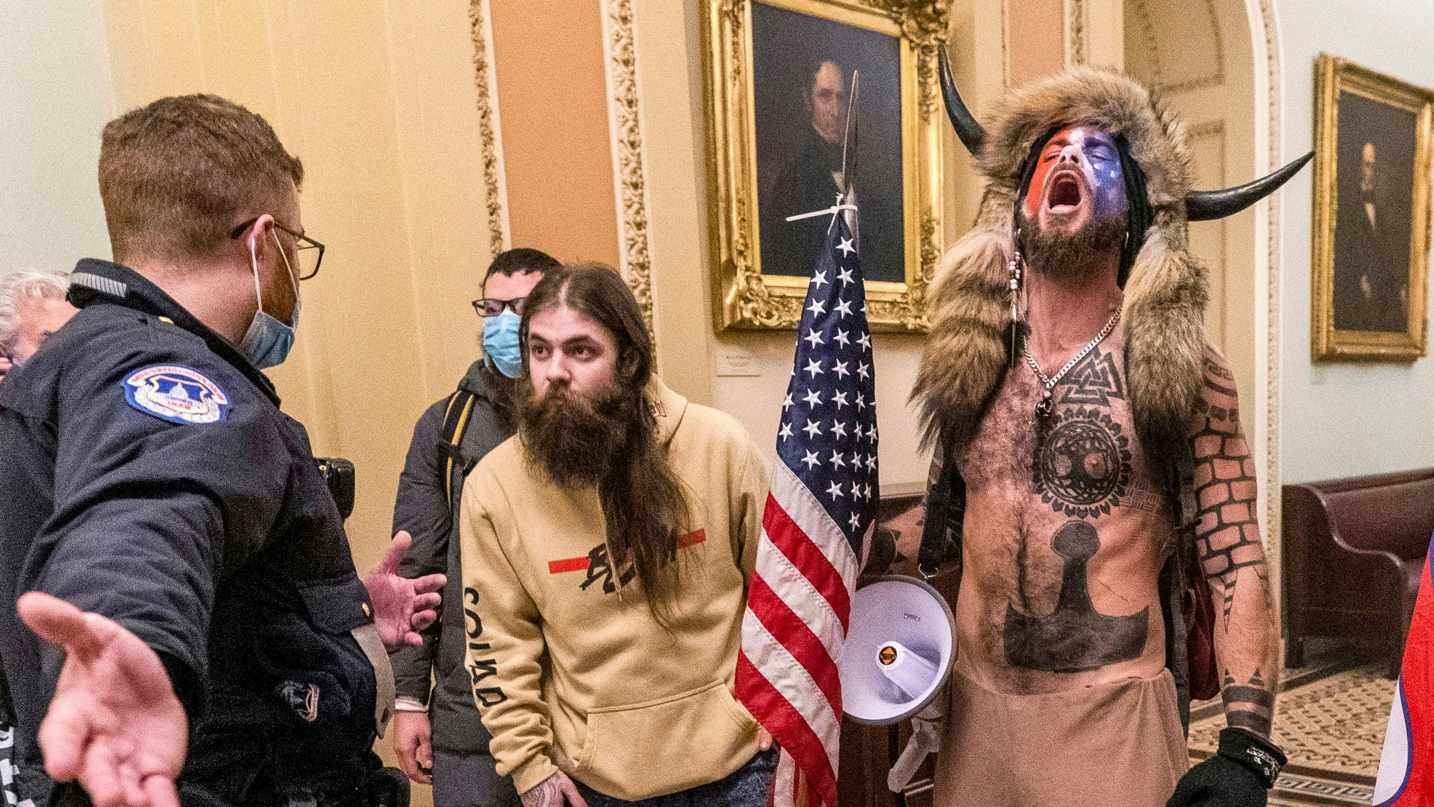 Download von www.picturedesk.com am 14.11.2023 (08:31).  FILE - In this Jan. 6, 2021 file photo, supporters of President Donald Trump, including Jacob Chansley, right with fur hat, are confronted by U.S. Capitol Police officers outside the Senate Chamber inside the Capitol in Washington. Many of those who stormed the Capitol on Jan. 6 cited falsehoods about the election, and now some of them are hoping their gullibility helps them in court. Albert Watkins, the St. Louis attorney representing Chansley, the so-called QAnon shaman, likened the process to brainwashing, or falling into the clutches of a cult. Repeated exposure to falsehood and incendiary rhetoric, Watkins said, ultimately overwhelmed his client's ability to discern reality. (AP Photo/Manuel Balce Ceneta, File) - 20210106_PD19068 - Rechteinfo: Rights Managed (RM)