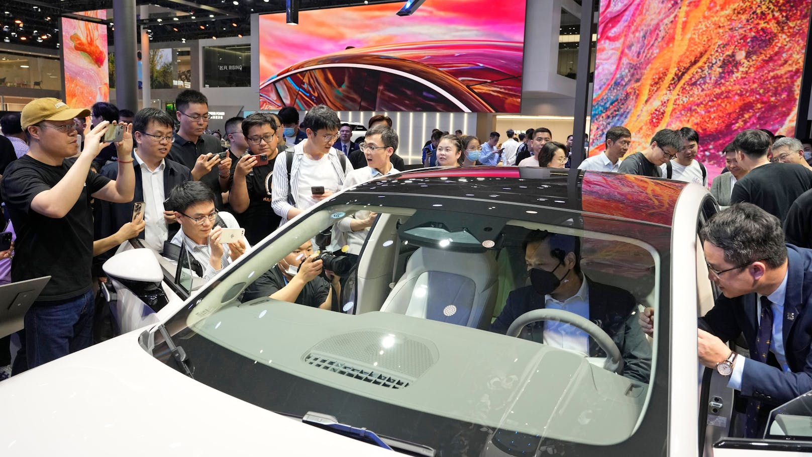 Xiaomi-Mitgründer Lei Jun (mit Maske im Auto) schaut sich ein Auto auf der Shanghai Automesse 2023 an. Nun scheint der chinesische Konzern auch ins E-Auto-Geschäft einsteigen zu wollen.