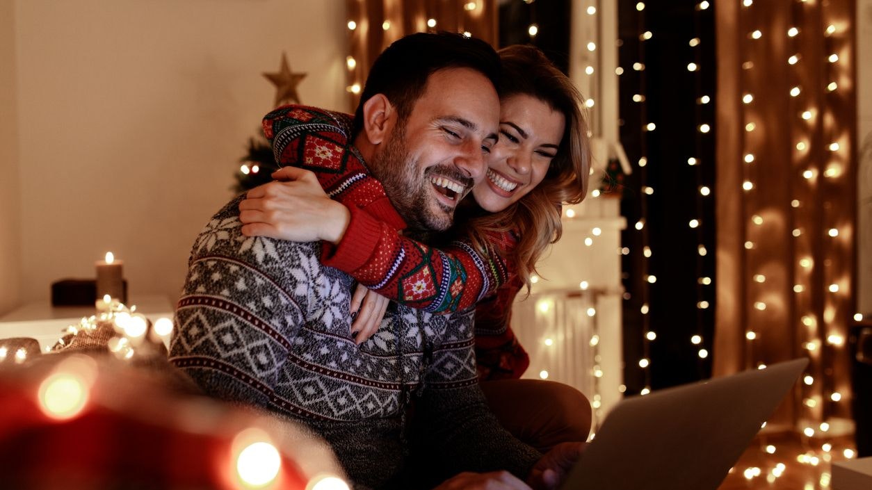Loving couple enjoying Christmas celebration at home by themselves. Surfing and buying presents online.