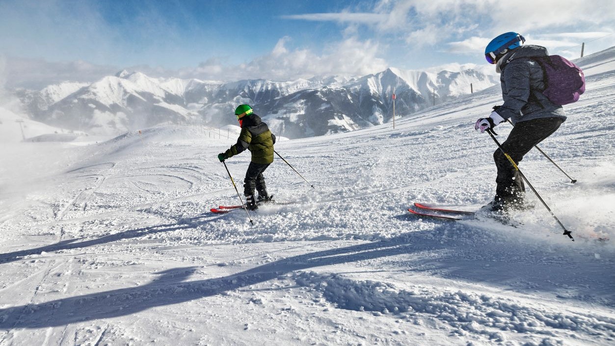 Mother and teenage son are skiing together in mountains on a sunny winter day.  Canon R5