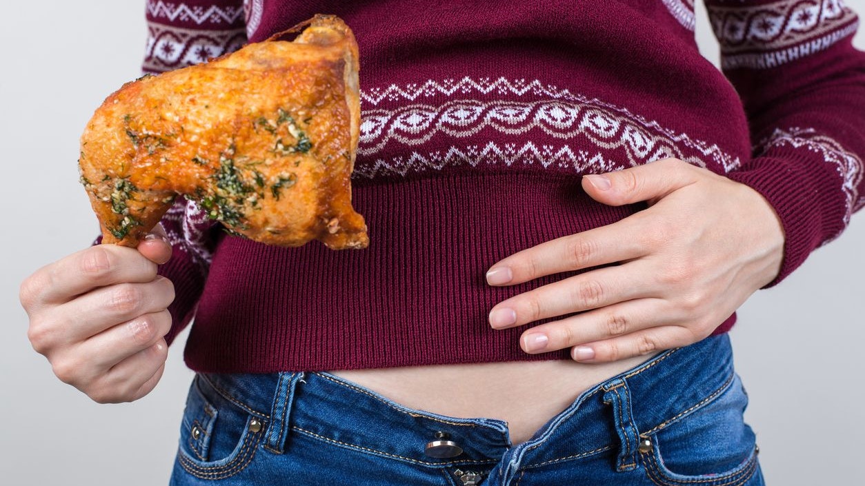 Junk food eating too much concept. Cropped close up photo of girl holding hands palm on big full abdomen feeling heartburn after fatty greasy nutrition isolated grey background