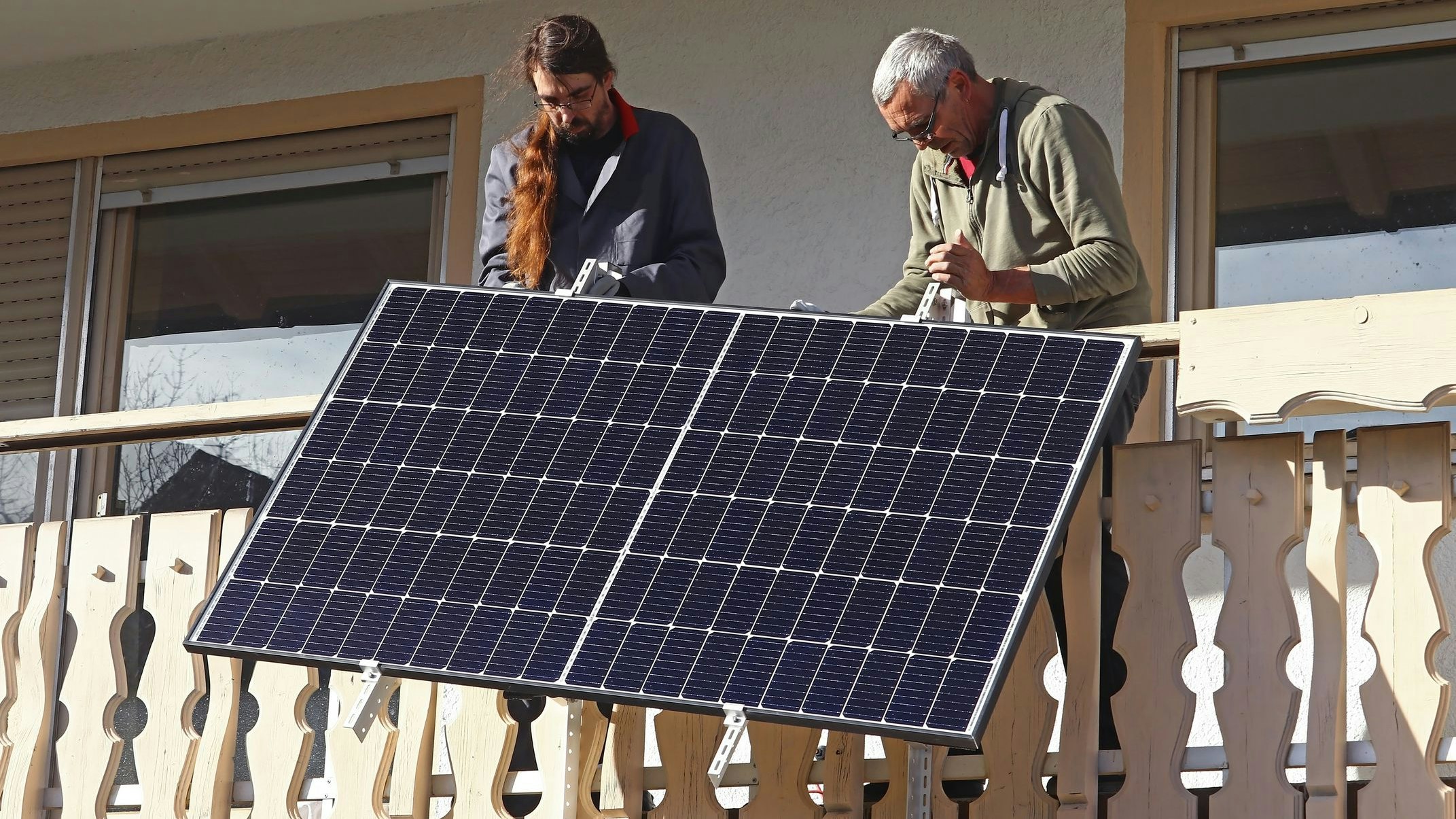 Two men assemble a balcony power plant to generate electricity