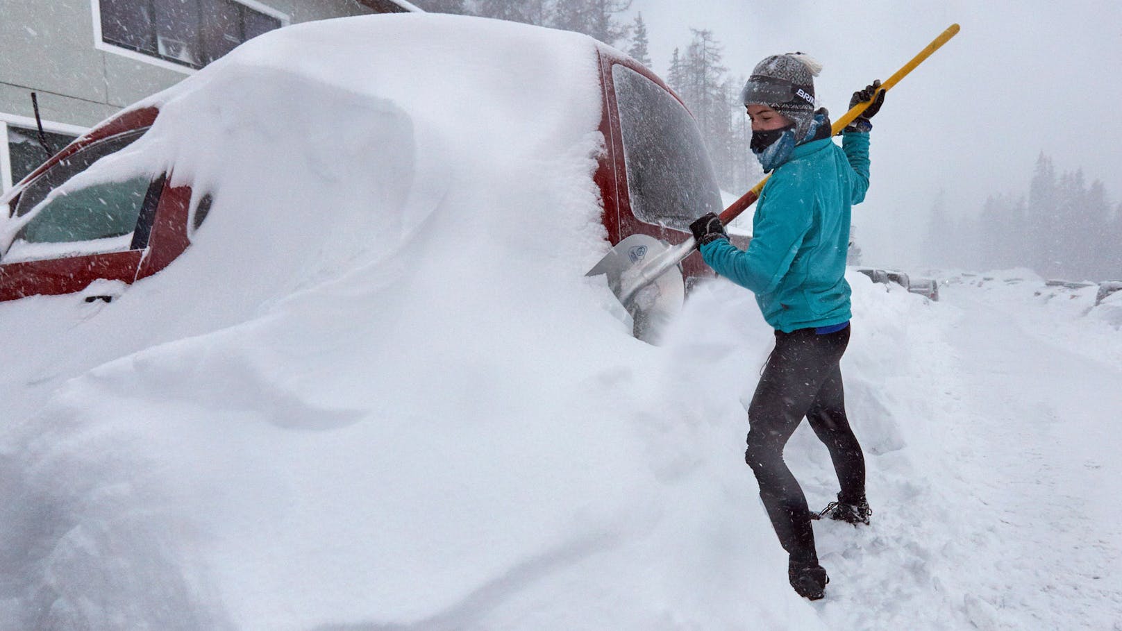 Eine Autofahrerin schaufelt nach starken Schneefällen ihr Fahrzeug aus. Archivbild.