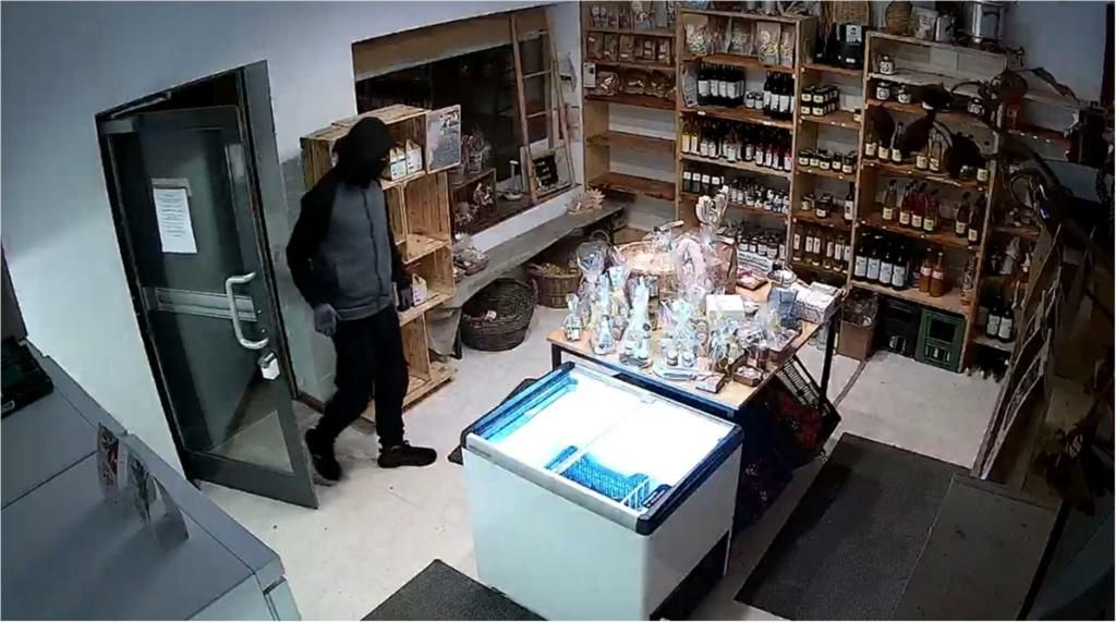 Der komplett in Schwarz gekleidete Täter mit Sturmhaube im Feinkost-Selbstbedienungsladen