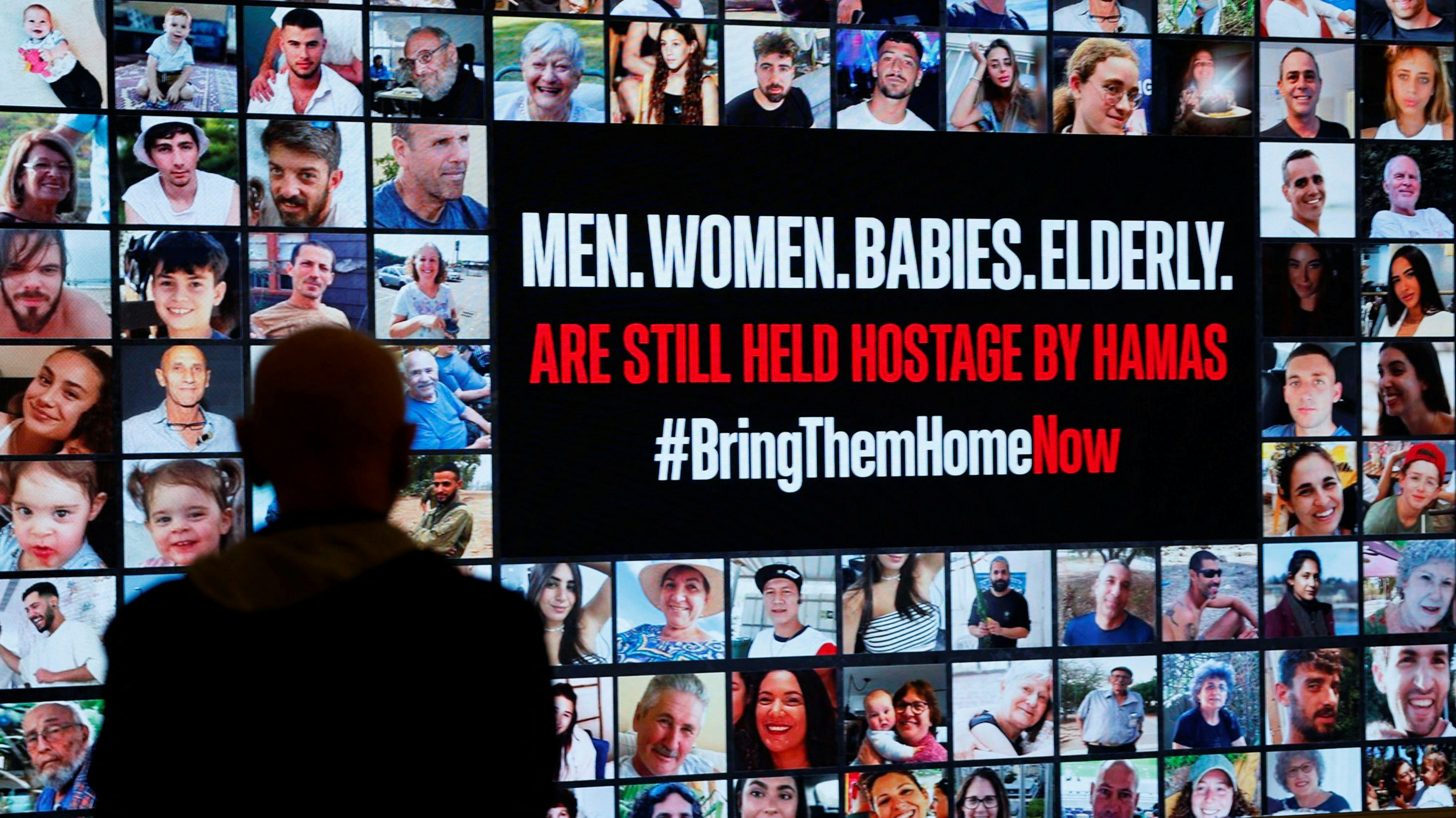 A person stands in front of pictures during a demonstration to demand the liberation of hostages who are being held in the Gaza Strip after they were seized by Hamas gunmen on October 7, in Tel Aviv, Israel November 21, 2023. REUTERS/Amir Cohen