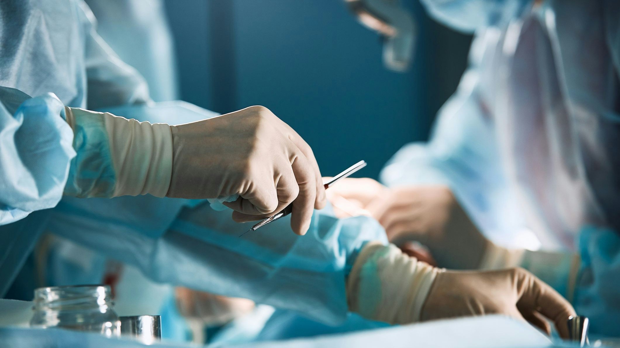 Doctor's hand with latex gloves taking stainless tweezers to help people with patience, on a white gray background. Modern medecine, life saving.