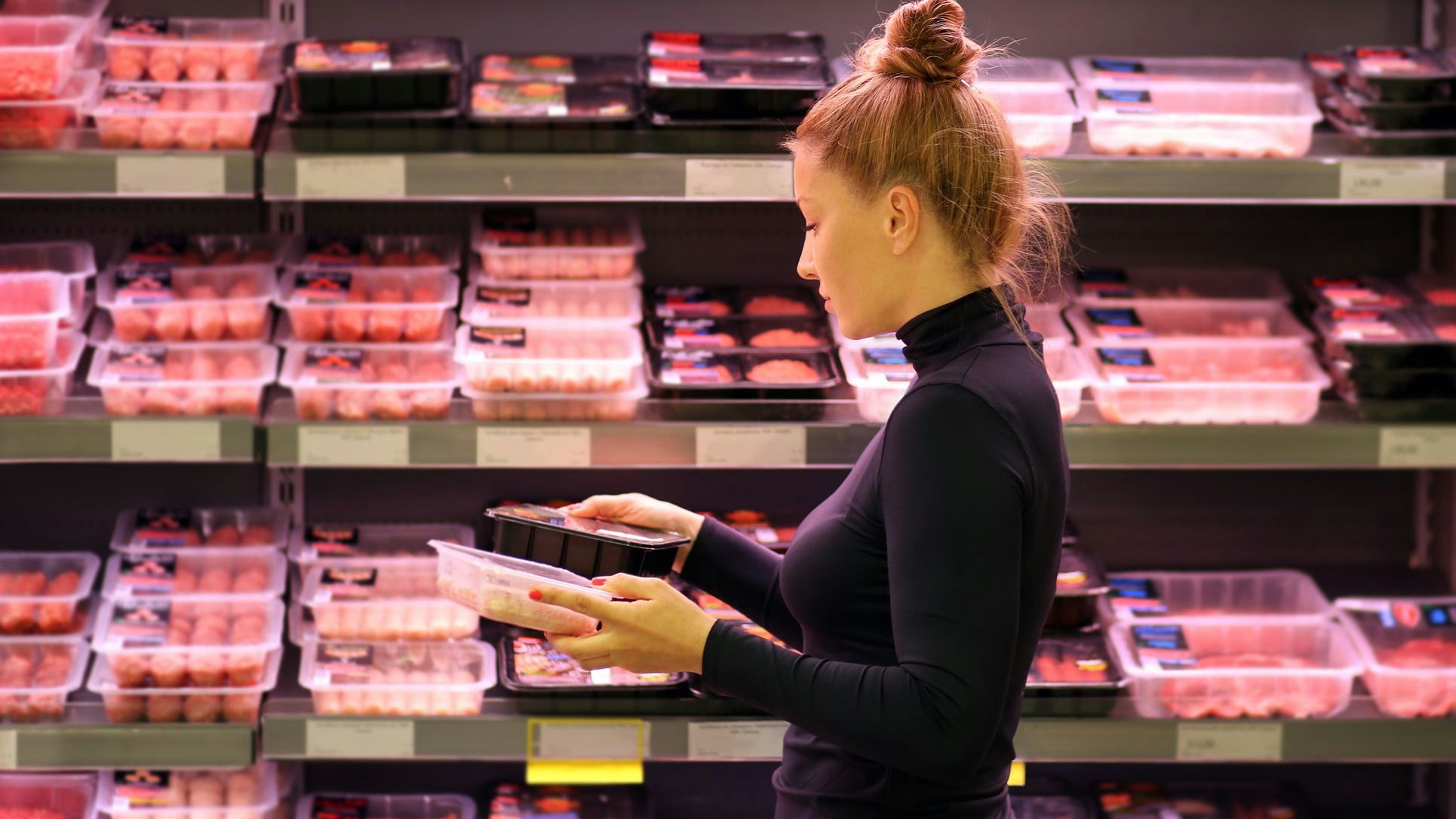 Woman purchasing a packet of meat at the supermarket