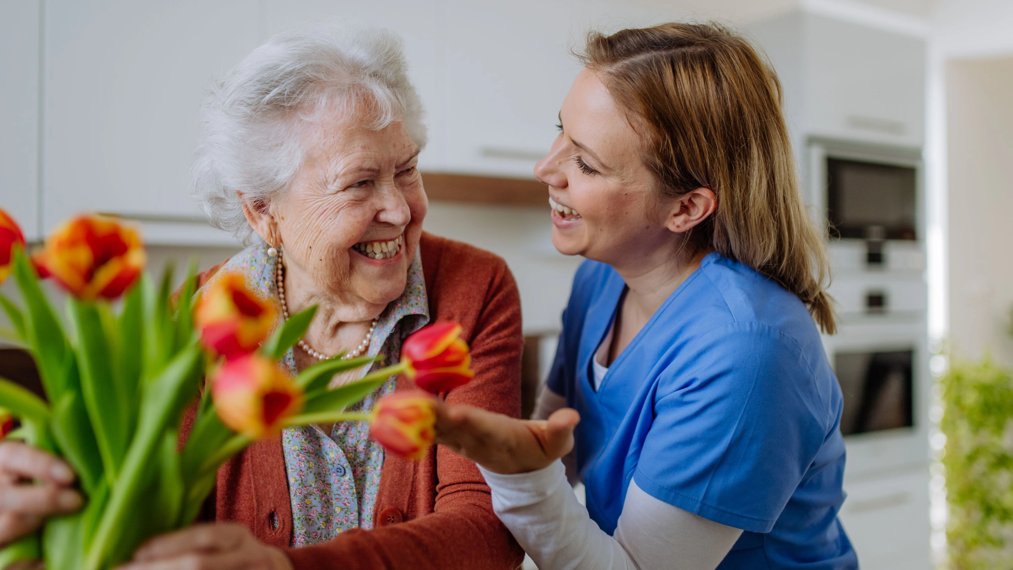 Senior woman and nurse with a tulip bouquet.