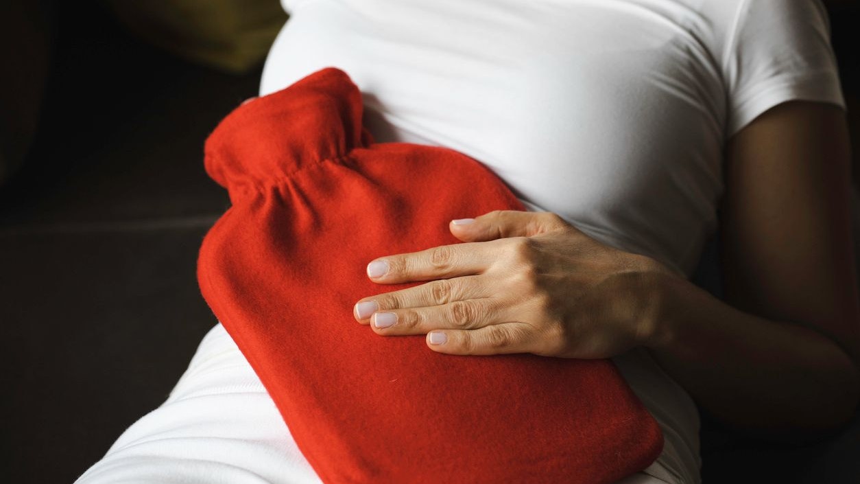 Unhealthy young woman with stomachache using a hot water bag.