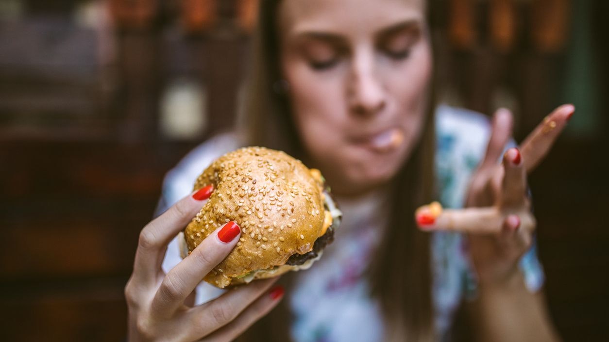 Gourmand Girl Eating Tasty Hamburger at Fast Food Restaurant