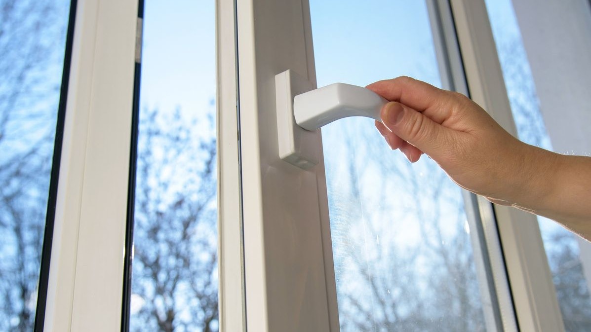 Hand opens vinyl plastic window on blue sky winter background. Oneped window.