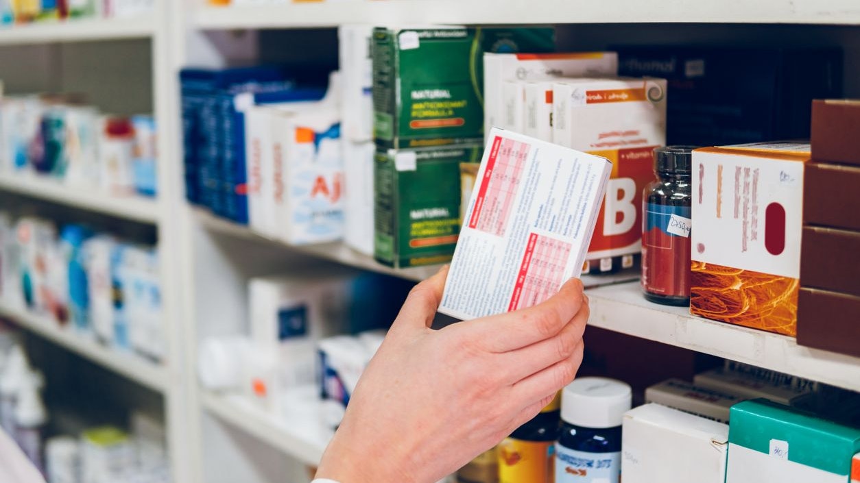 A young female pharmacist arranges medicines on the shelves of the pharmacy and makes an inventory.