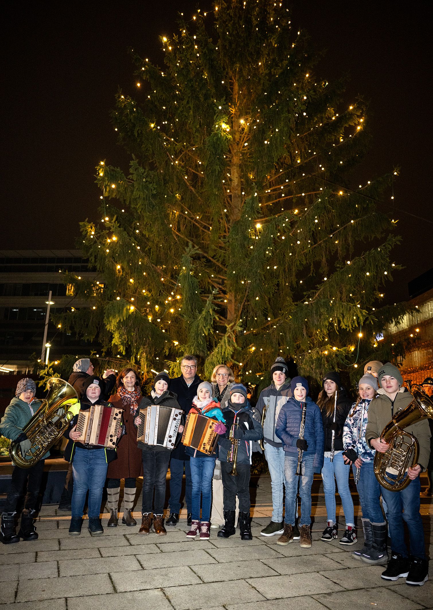 Landeshauptfrau Johanna Mikl-Leitner und Bürgermeister Josef Forster mit den jungen Musikantinnen und Musikanten der Musikschule Ertl vor dem illuminierten Landhaus-Christbaum.