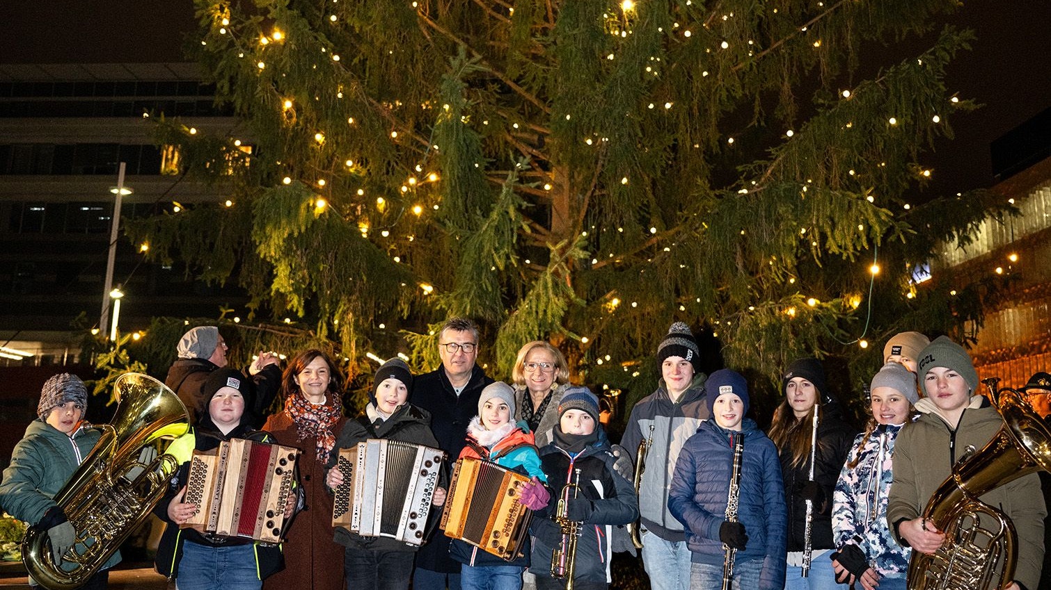Landeshauptfrau Johanna Mikl-Leitner und Bürgermeister Josef Forster mit den jungen Musikantinnen und Musikanten der Musikschule Ertl vor dem illuminierten Landhaus-Christbaum.