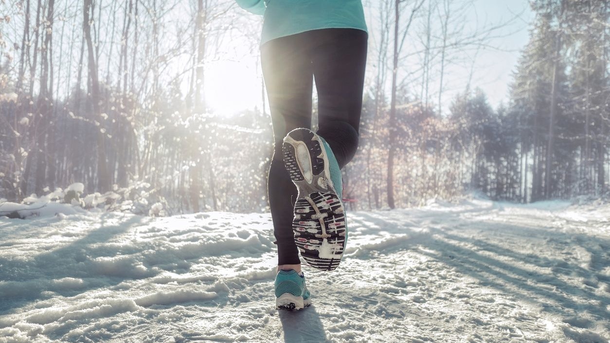Woman Running at snowly winter under sunlight.