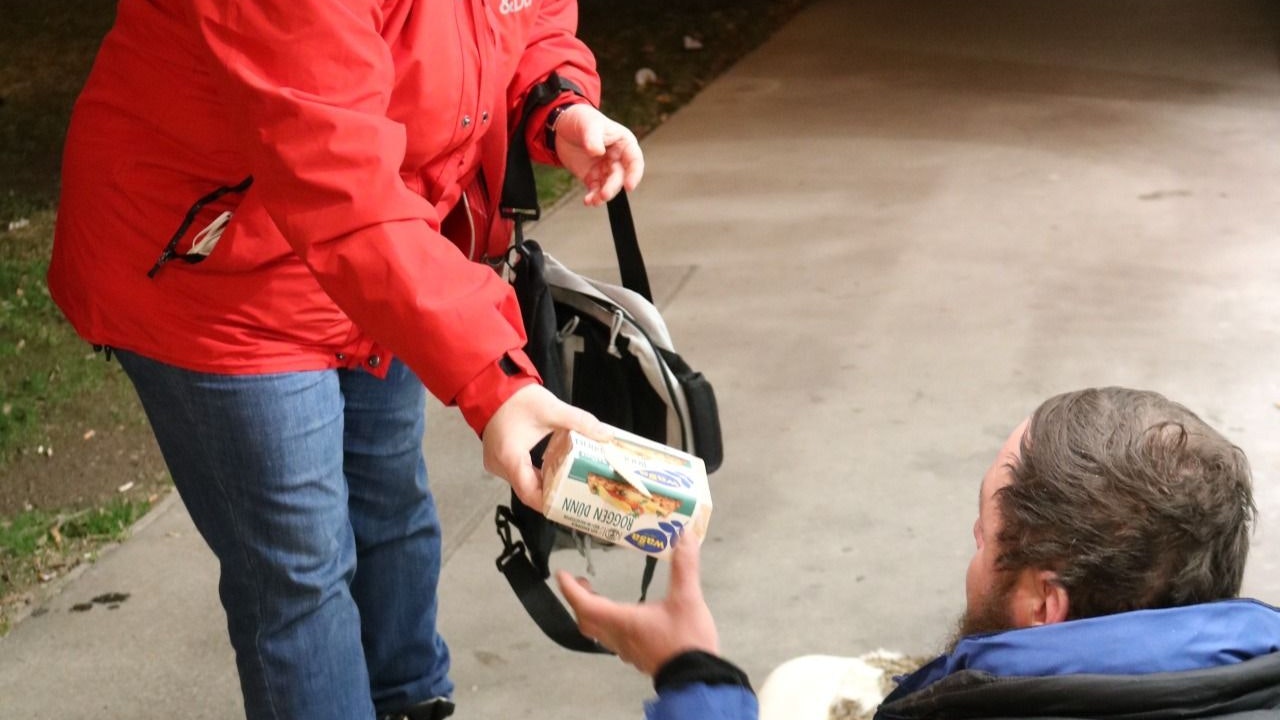Die Caritas Mitarbeiter geben Obdachlosen warmes Essen und Getränke.