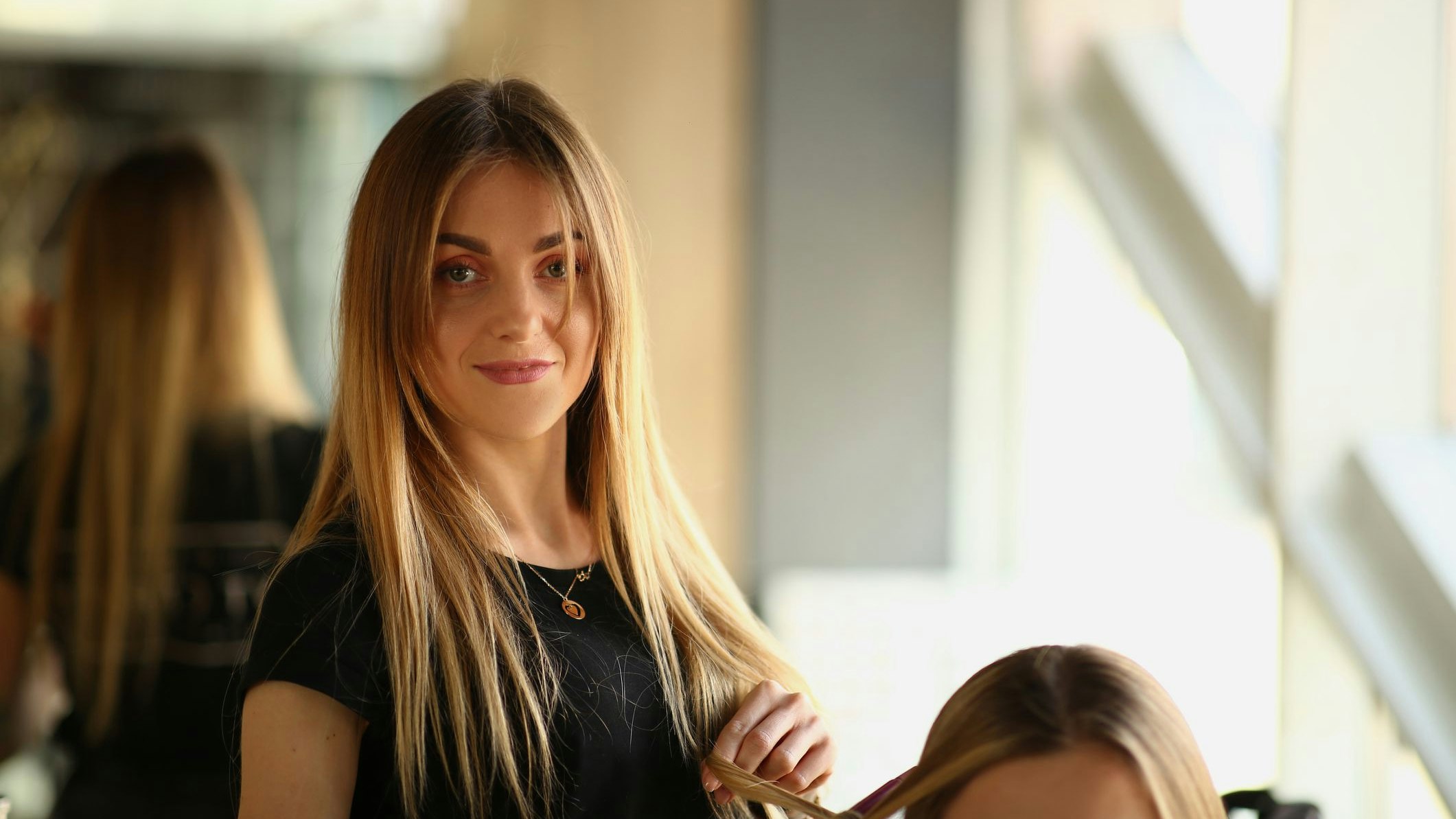 Woman hairdresser makes haircut to woman in beauty salon. Trainee learning to do party hairstyles in barbershop