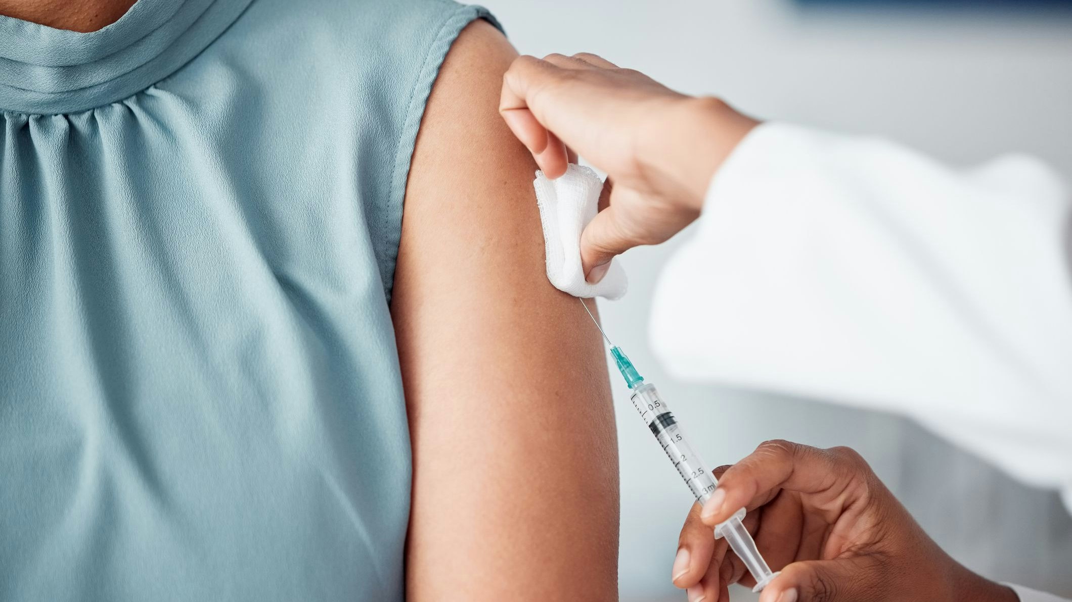 Hands, medical and doctor with patient for vaccine in a clinic for healthcare treatment for prevention. Closeup of a nurse doing a vaccination injection with a needle syringe in a medicare hospital.