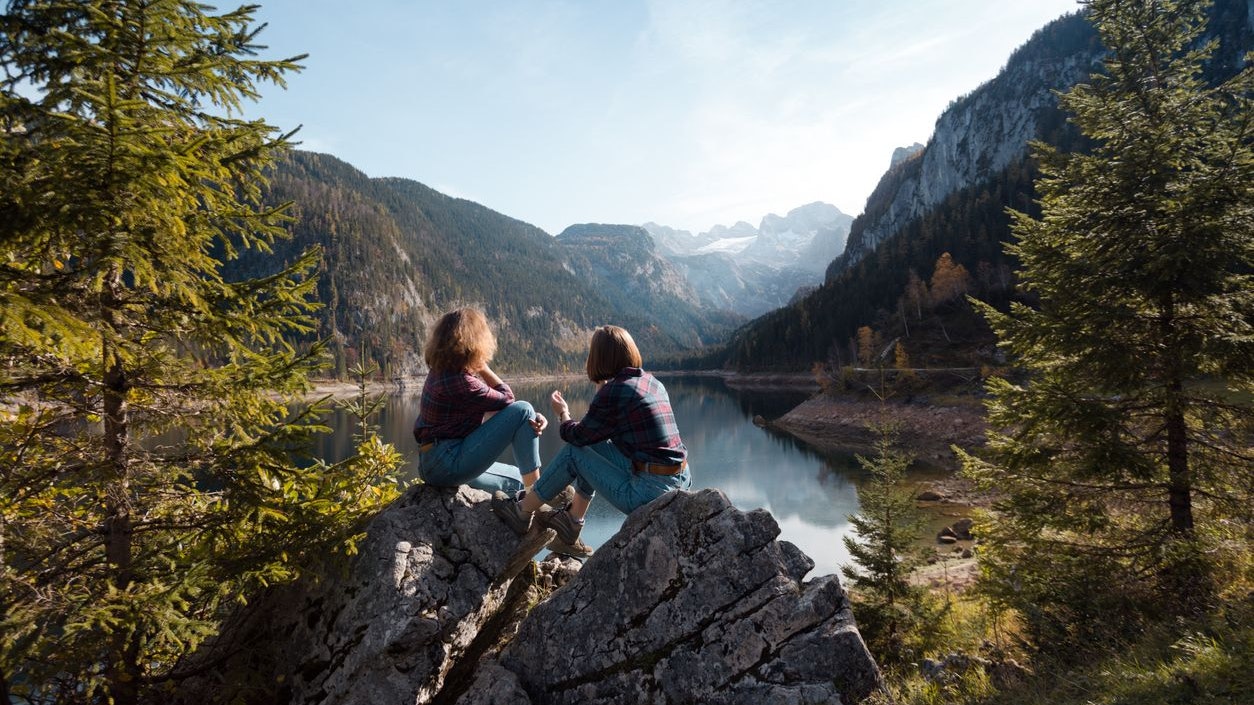 mountain trip. two happy girls on the background of a mountain lake and mountains in the background"n