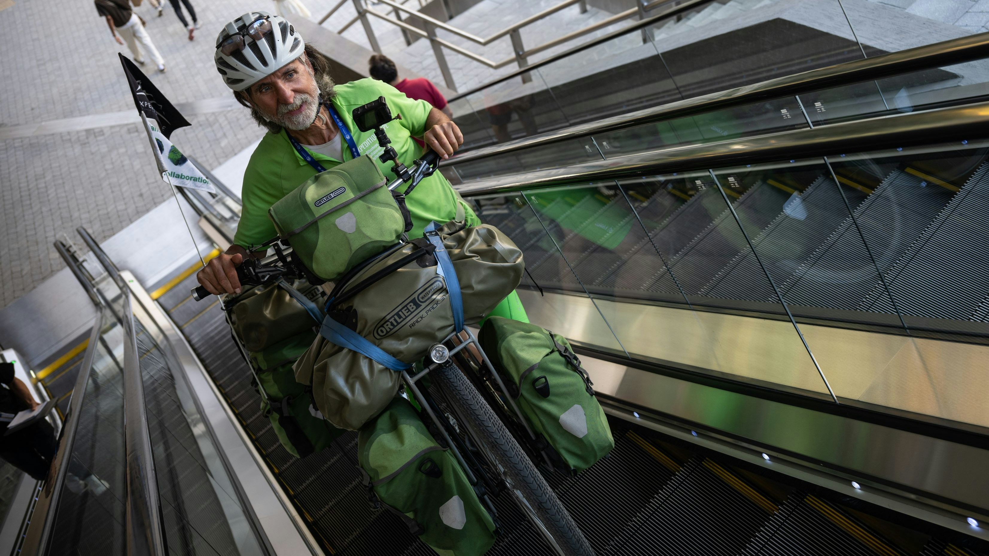 Download von www.picturedesk.com am 12.12.2023 (13:04).  10 December 2023, United Arab Emirates, Dubai: Michael Evertz, environmentalist, rides his bike up an escalator. The environmentalist has traveled from Berlin to Dubai by bike. Photo: Hannes P. Albert/dpa - 20231210_PD3685 - Rechteinfo: Rights Managed (RM)