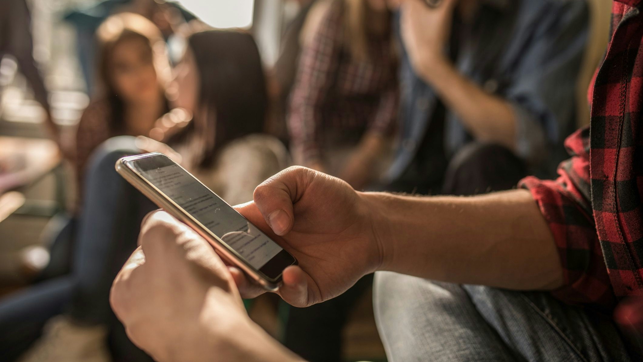 Unrecognizable male student text messaging on mobile phone while being on a break in the classroom.