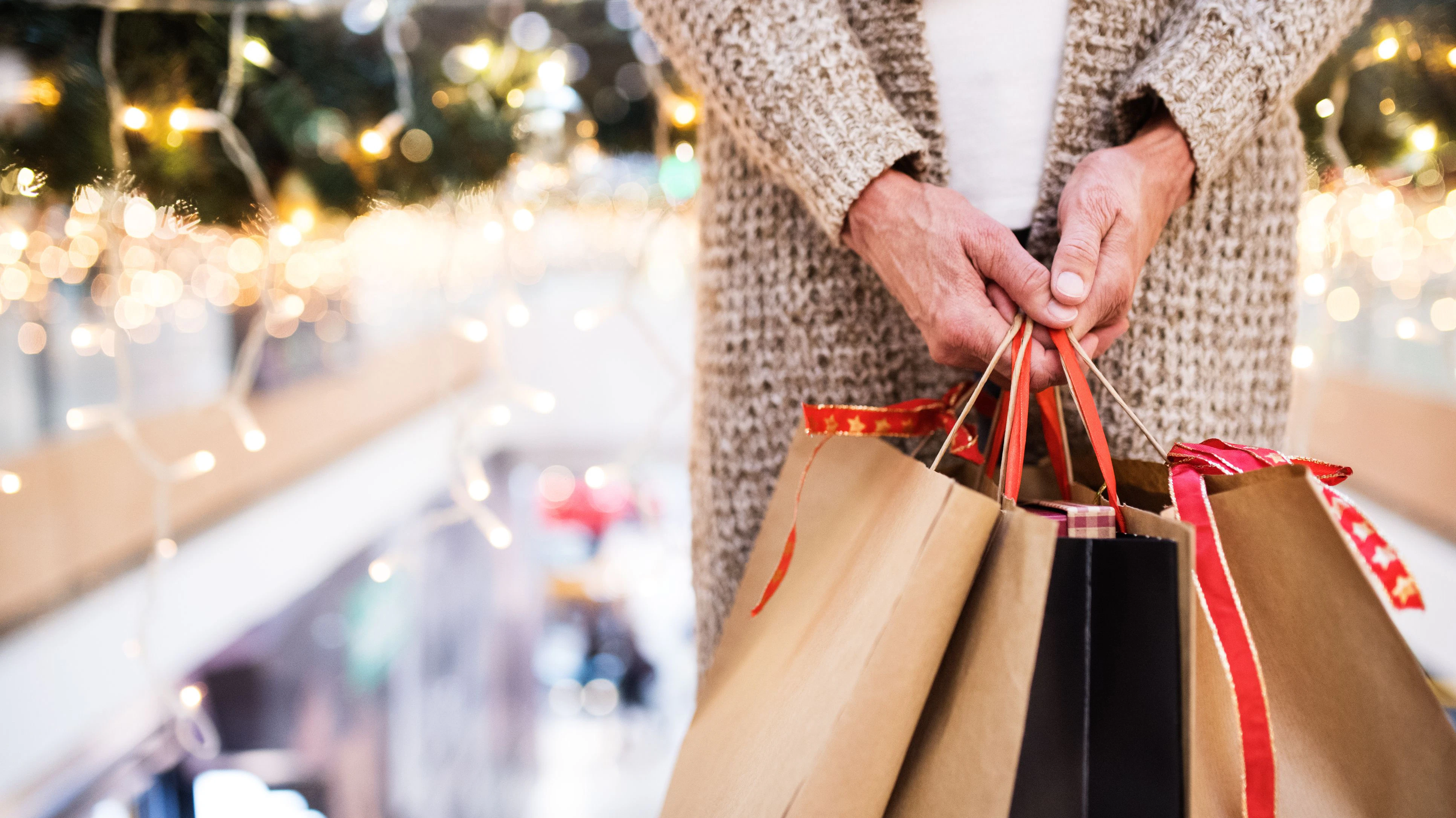 Unrecognizable senior woman with paper bags doing Christmas shopping. Shopping center at Christmas time.