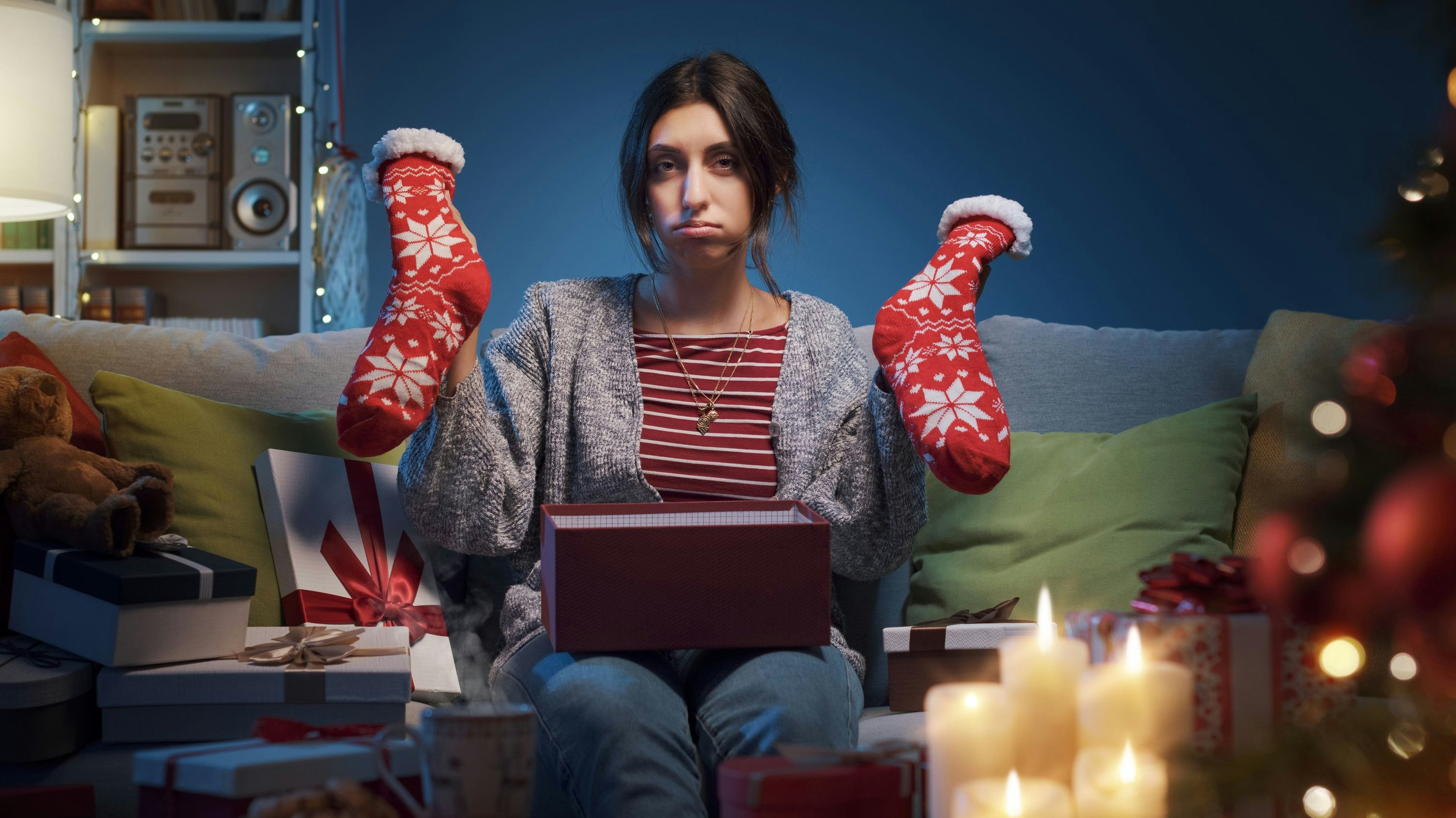 Sad disappointed woman opening Christmas gifts at home, she received Christmas socks