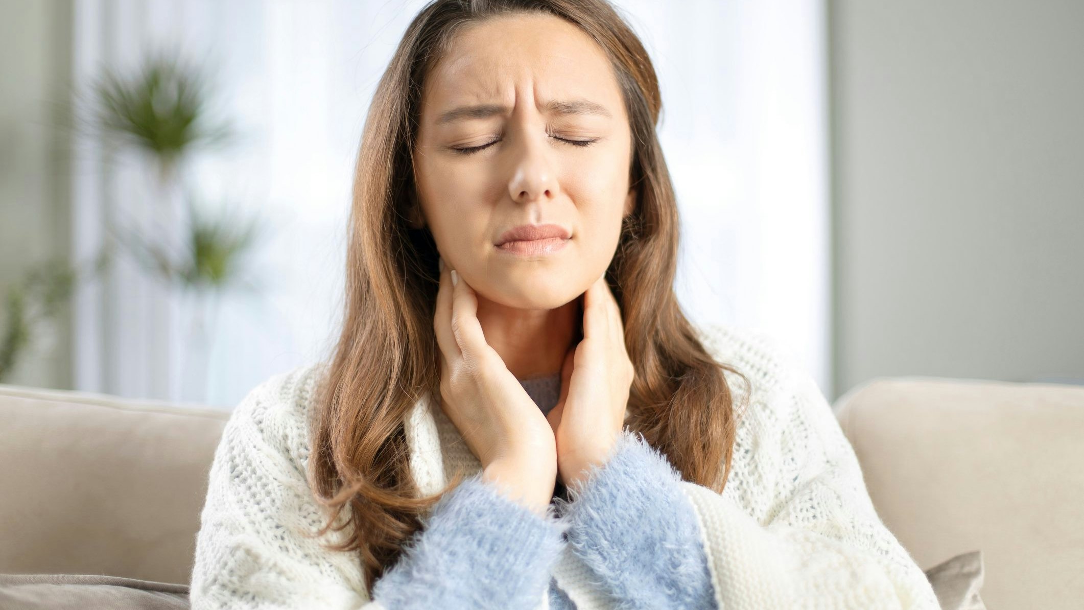 Young woman touching painful neck, sore throat for flu, cold and infection