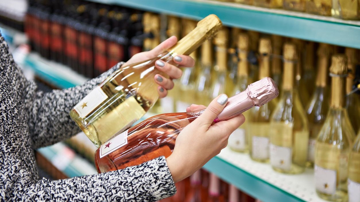 Woman with bottles of rose and white wine in the store
