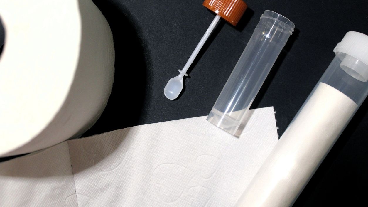 Stool sample: tube and small spoon for a medical examination of the stool. Toilet paper.  An important examination for the prevention of bowel cancer.