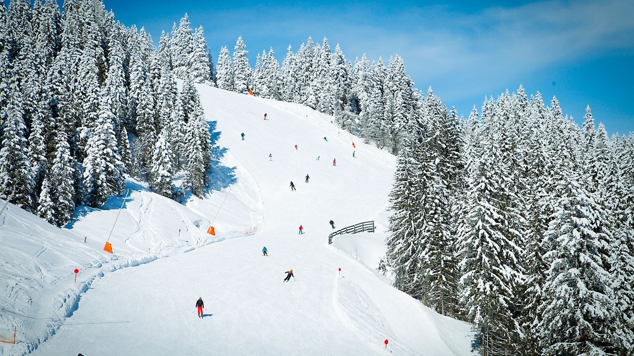 Ski slope with skiers in Austrian Alps mountains