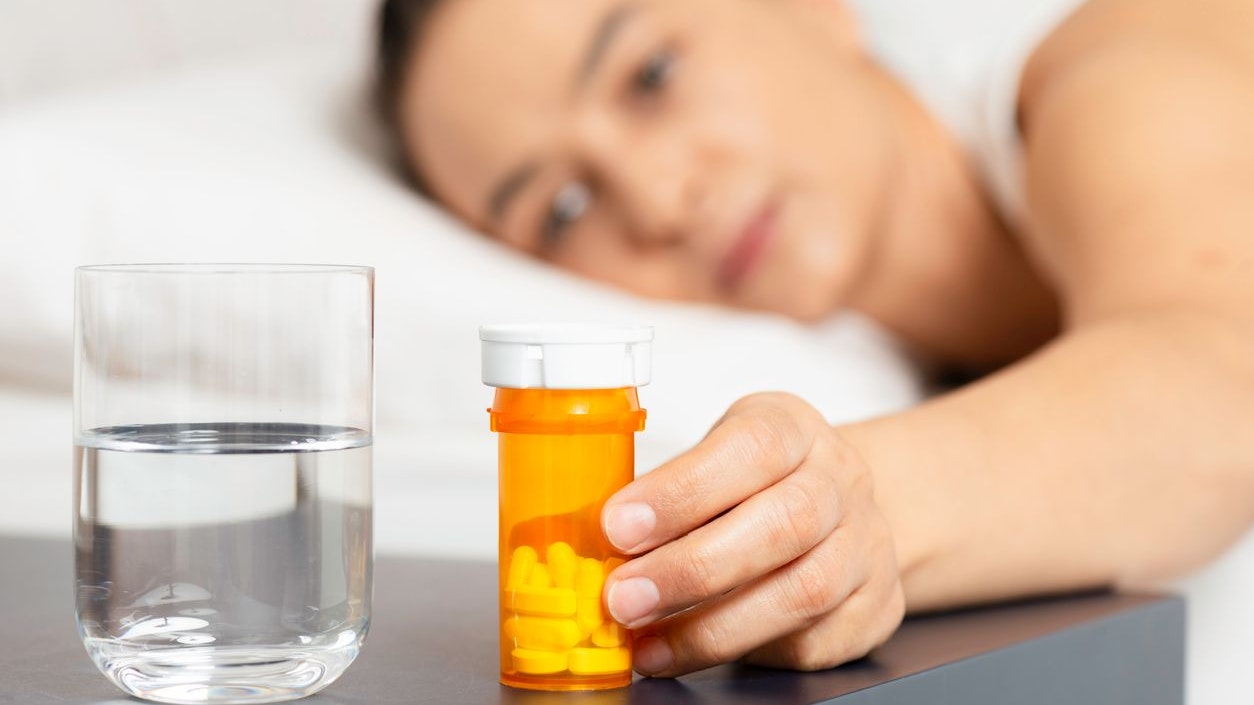 Caucasian female is about to take medication in bed.