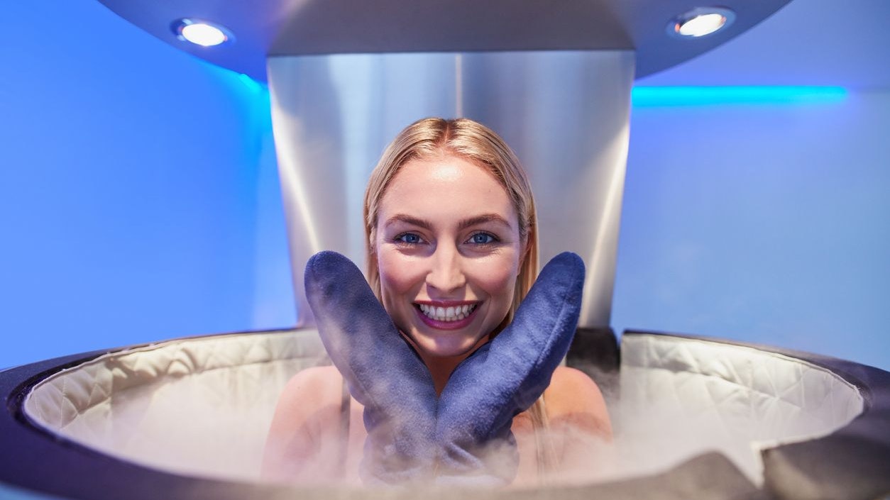 Portrait of a cute young woman in cryosauna booth for full body cryotherapy. Caucasian female in freezing chamber with nitrogen vapors.