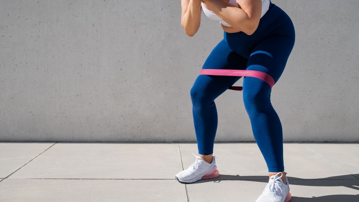 Woman exercising outdoors with resistance band around thighs