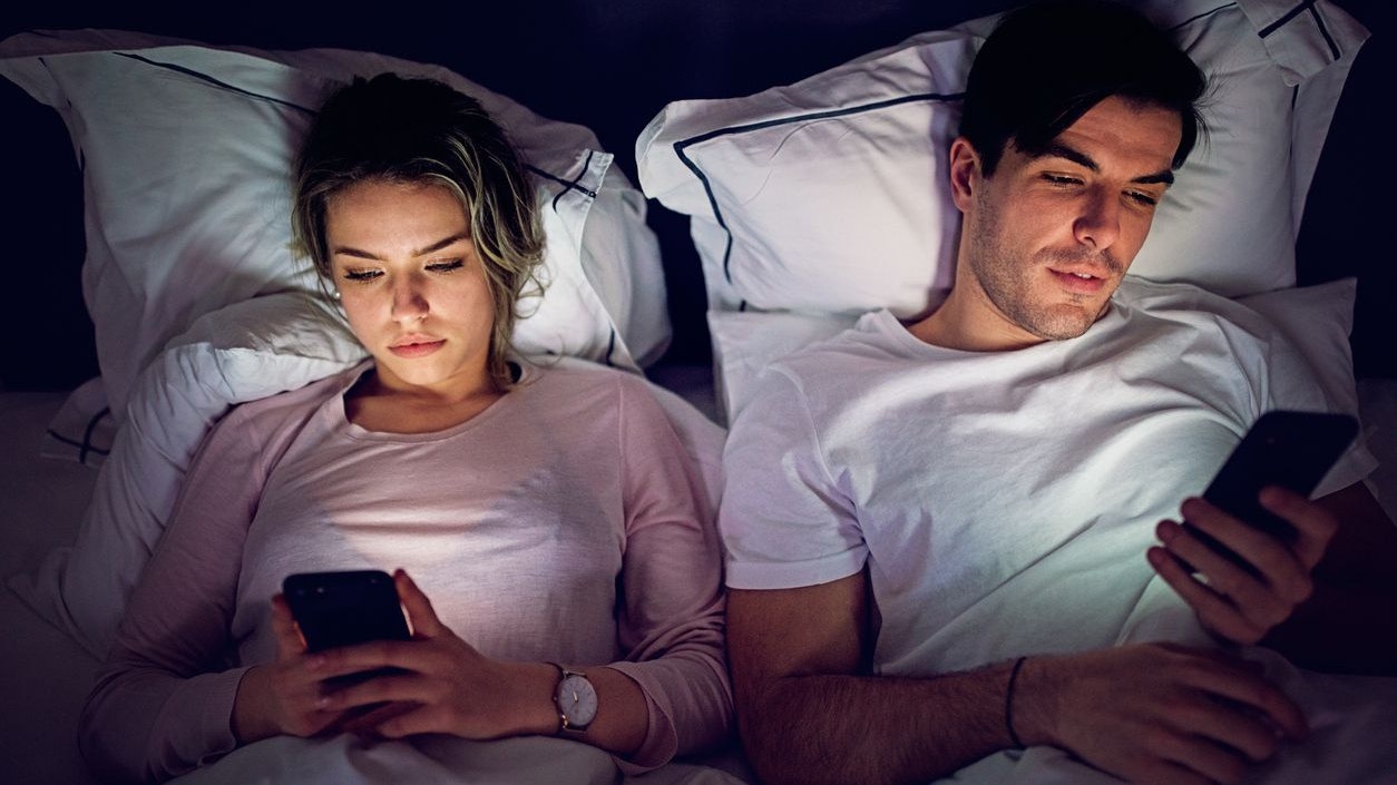 Mobile phone addiction - couple is texting and browsing in the bed