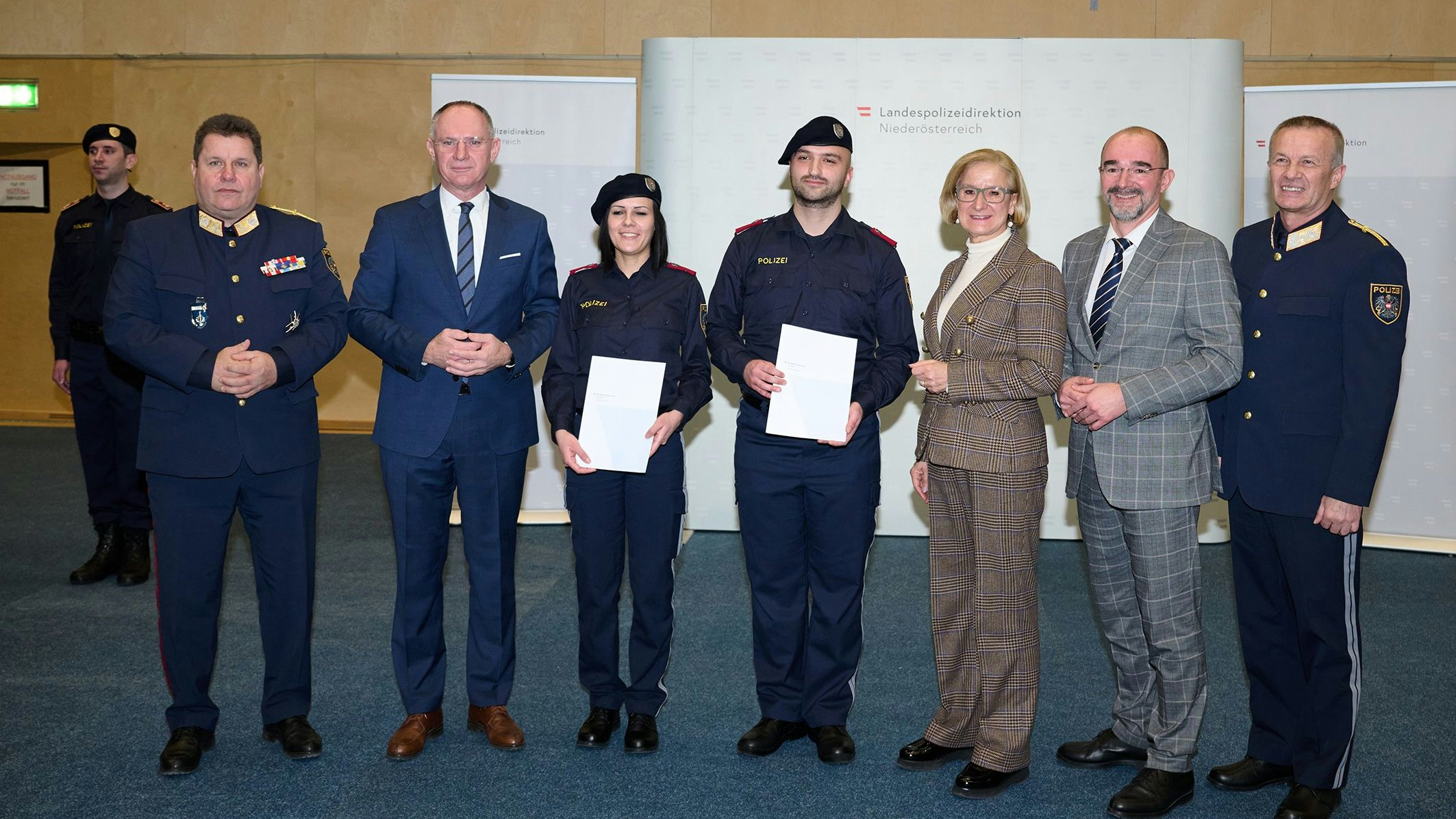 Bundespolizeidirektor Michael Takacs, Innenminister Gerhard Karner, Kerstin Karner, Emre Cakir, Landeshauptfrau Johanna Mikl-Leitner, Sektionschef Karl Hutter und Landespolizeidirektor Franz Popp bei der Übergabe der Dienstprüfungszeugnisse.